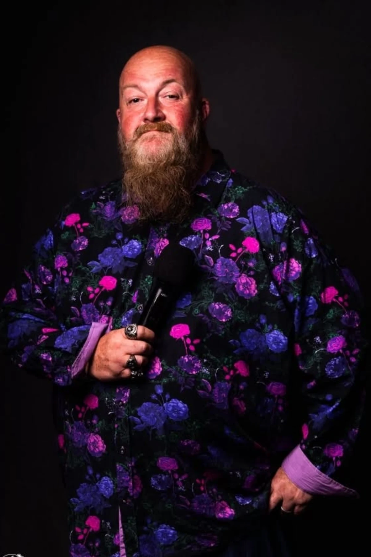 Pete Murphy holding a microphone, wearing a purple floral shirt